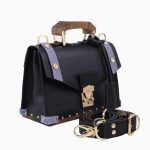 Sac à main Fiona, avec une texture en cuir noir et des accents en cuir violet. Il présente une poignée en bois, des fermetures dorées et une bandoulière assortie, offrant un design élégant et sophistiqué.