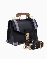 Sac à main Fiona, avec une texture en cuir noir et des accents en cuir violet. Il présente une poignée en bois, des fermetures dorées et une bandoulière assortie, offrant un design élégant et sophistiqué.