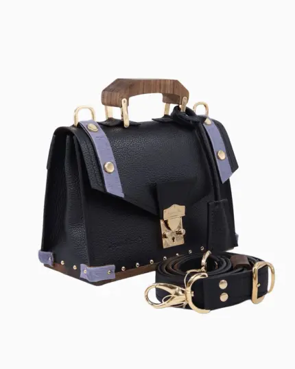 Sac à main Fiona, avec une texture en cuir noir et des accents en cuir violet. Il présente une poignée en bois, des fermetures dorées et une bandoulière assortie, offrant un design élégant et sophistiqué.